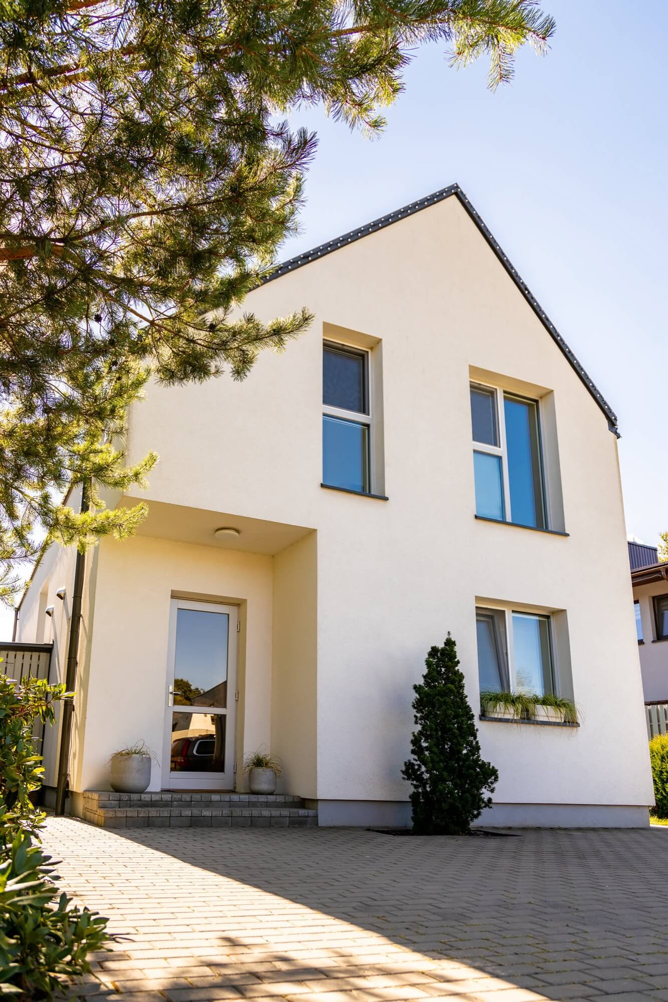 Entrén till en modern vit villa med putsad fasad, byggd som en del av en bostadsentreprenad.