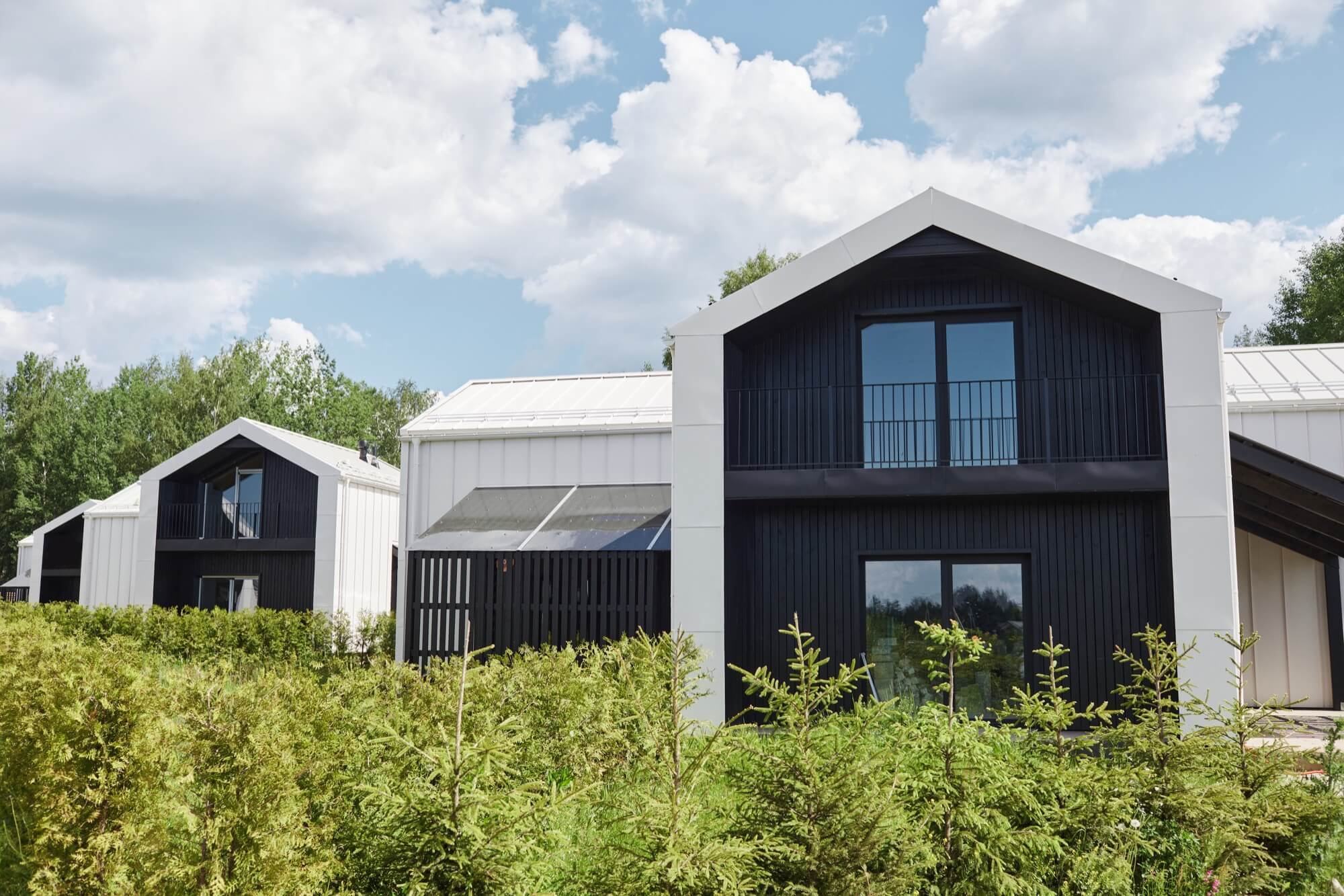 Moderna nybyggda hus med svartvit fasad, ett resultat av en lyckad entreprenad i ett nytt bostadsområde.