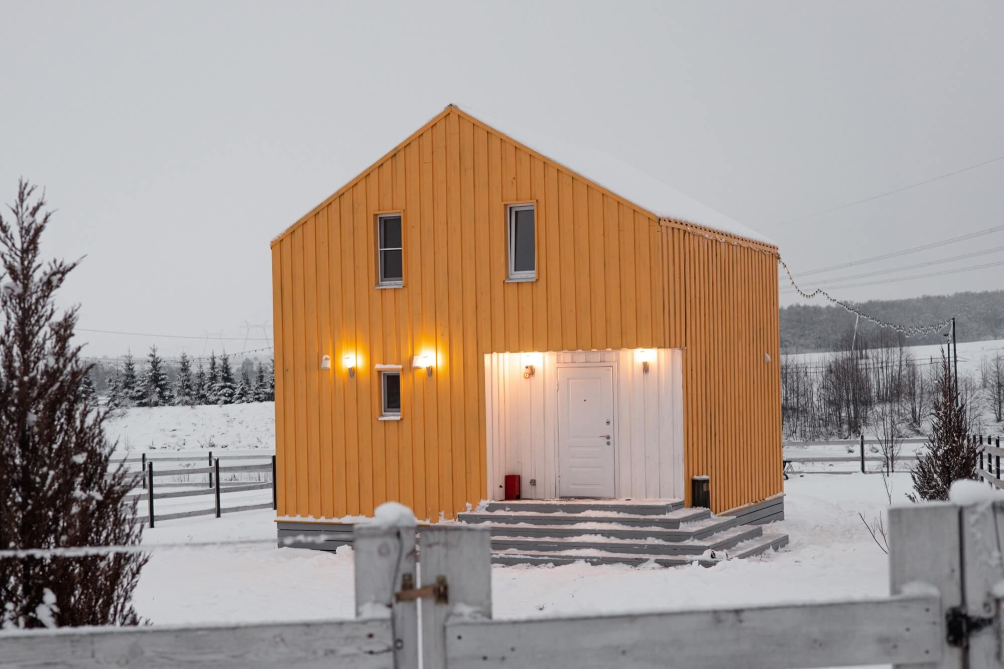 Ett nybyggt gult trähus i ett snöigt vinterlandskap, ett slutfört entreprenad-projekt.